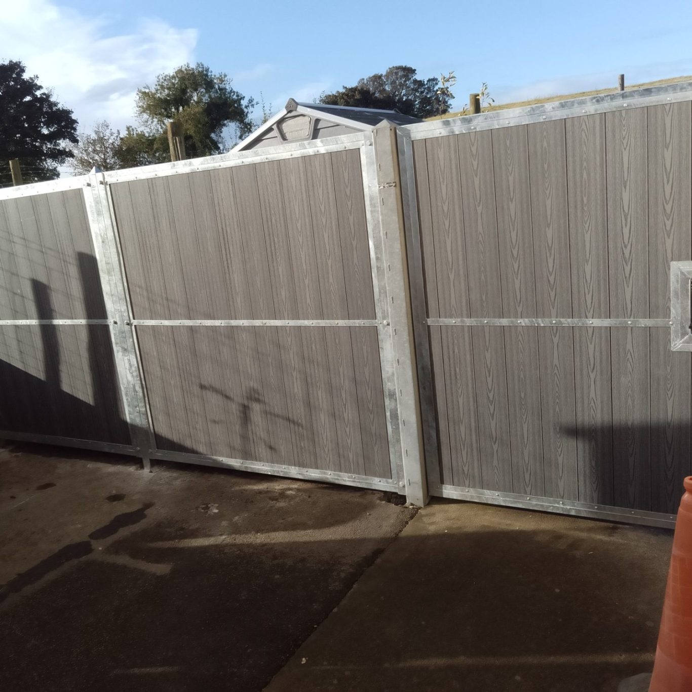 a tall privacy fence and gate made from a galvanised steel frame with grey composite board infills