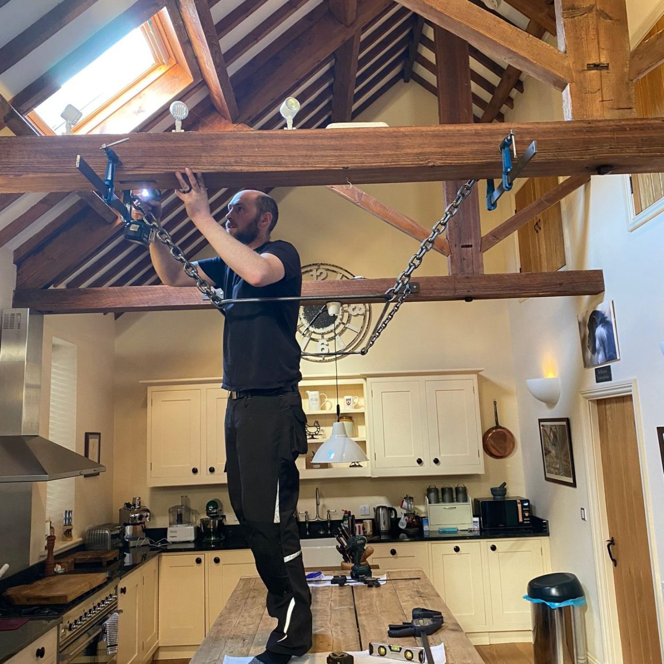 Glenview Steel installing a large metal chain pan rack above a kitchen island